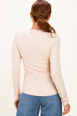 woman wearing a light beige long sleeve ribbed top with a fitted silhouette and a round neckline, viewed from the back