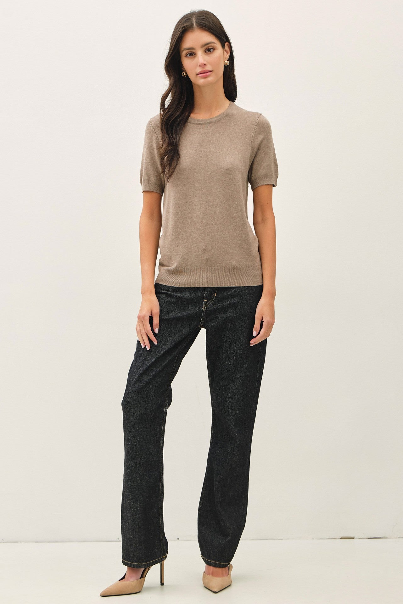 woman wearing a beige short sleeve knit top and high-waisted black jeans with pointed beige heels