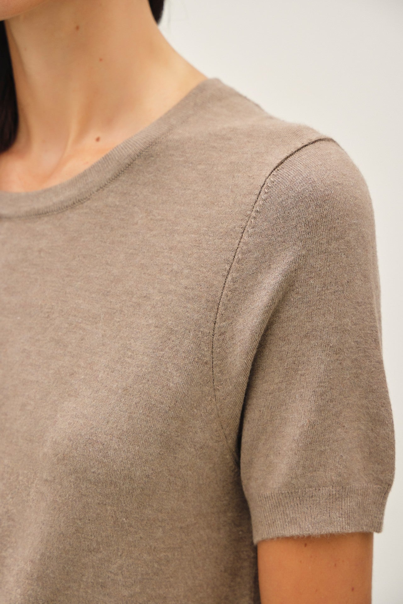 woman wearing a taupe short sleeve knit sweater with a round neckline and soft texture