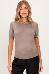 woman wearing a taupe short sleeve maternity sweater with a fitted style and a visible baby bump