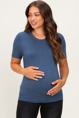 woman wearing a blue short sleeve maternity top and holding her baby bump