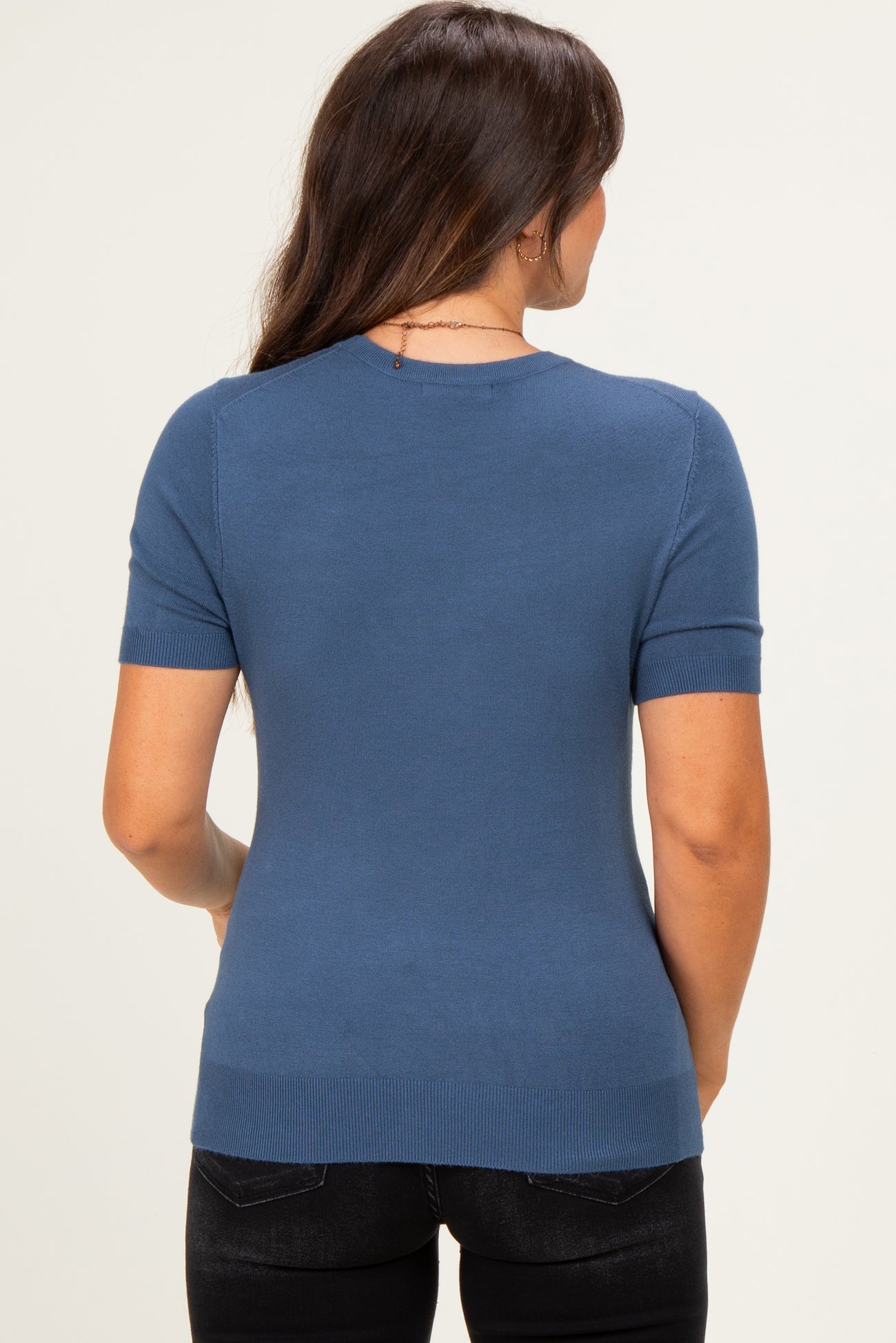 woman wearing a blue short sleeve maternity sweater, view from the back, fitted style