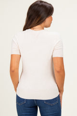 woman wearing a light beige short sleeve maternity top with a fitted silhouette, viewed from the back