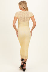 woman wearing a yellow lace maternity dress with short sleeves and a fitted silhouette, showing a pregnant belly