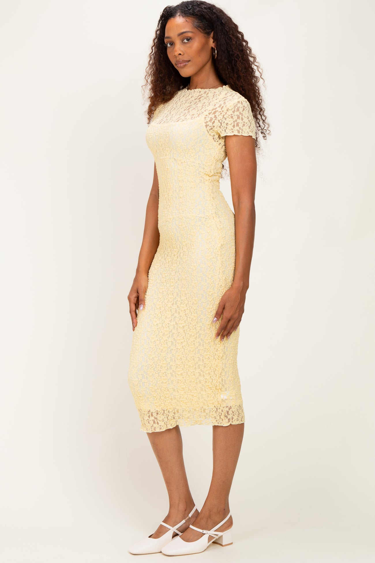 woman wearing a yellow lace midi dress with short sleeves and a fitted silhouette