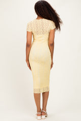 woman wearing a fitted yellow lace midi dress with short sleeves, showing a back view