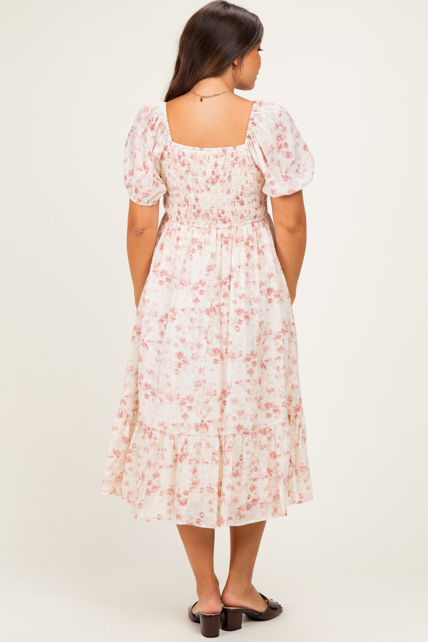 woman wearing a floral print maternity dress with puff sleeves and a tiered hem, showing off her baby bump