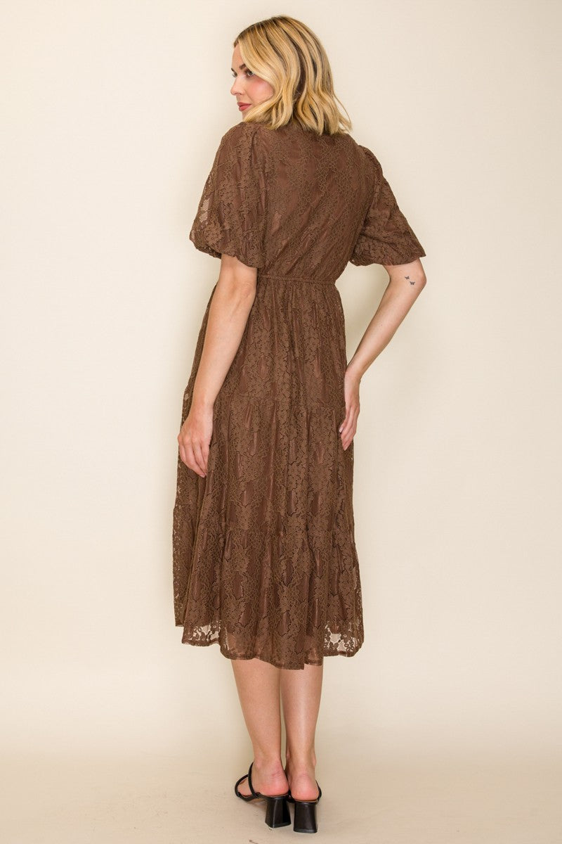 woman wearing a brown lace midi dress with short sleeves and a cinched waist, shown from the back