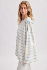 woman wearing a cream and light blue striped long sleeve oversized top with a relaxed fit and round neckline