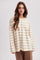 woman wearing a cream long sleeve striped top with brown horizontal stripes paired with brown pants
