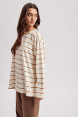 woman wearing a cream long sleeve striped top with brown stripes and relaxed fit, styled with brown trousers