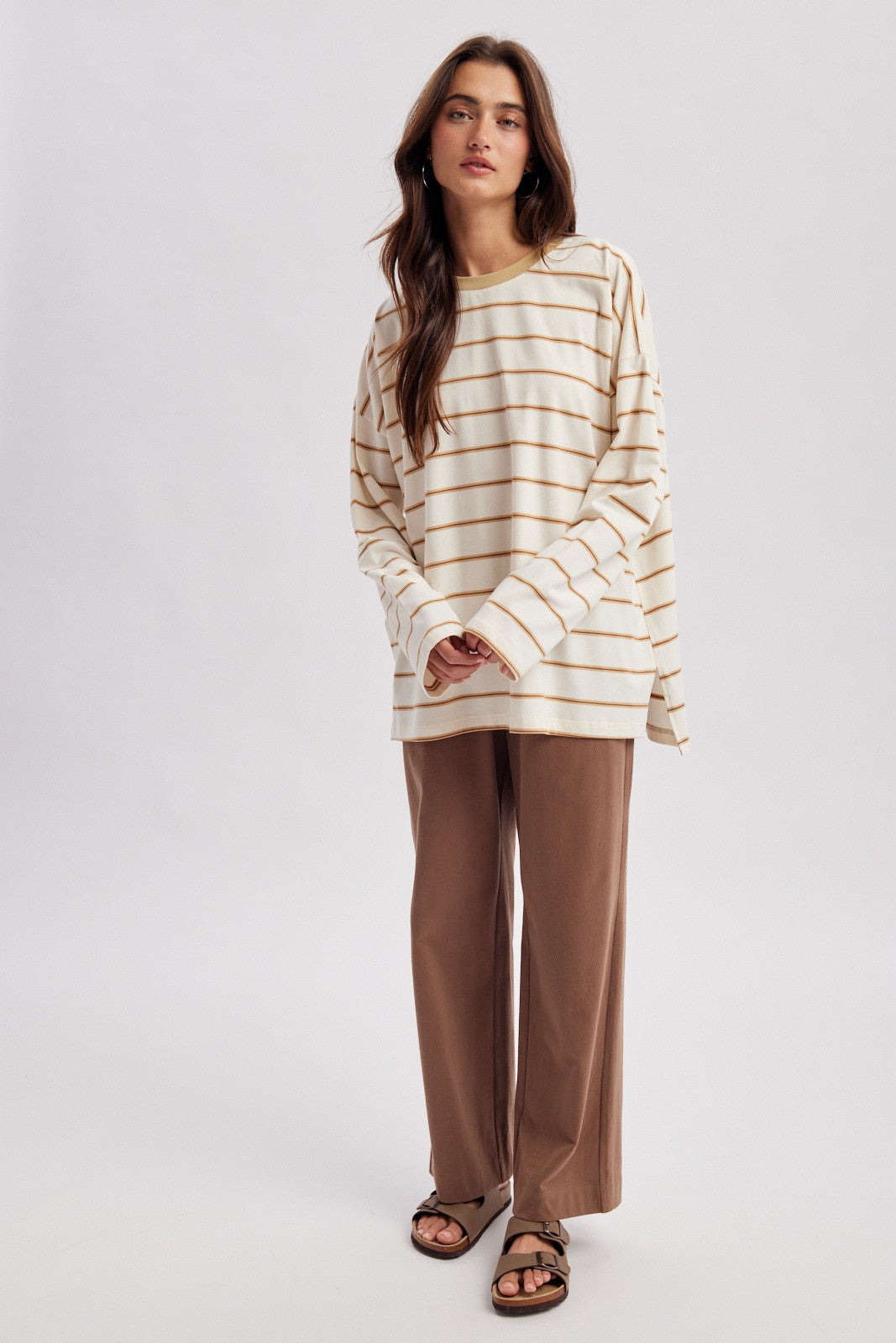 woman wearing a cream and tan striped long sleeve top with brown wide leg trousers and sandals