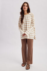 woman wearing a cream and tan striped long sleeve top with brown wide leg trousers and sandals