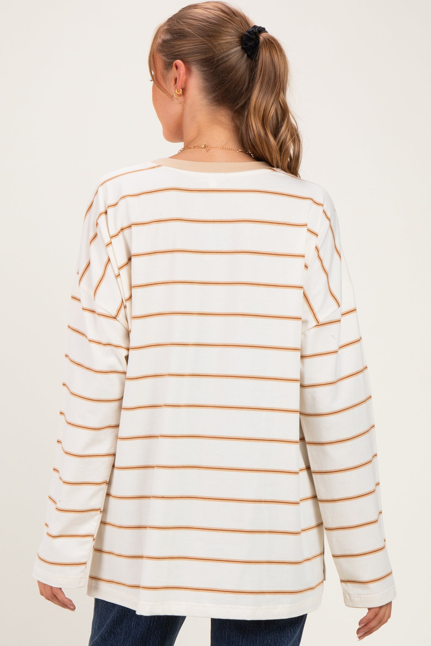 woman wearing a beige and cream striped long sleeve maternity top viewed from the back