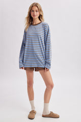 woman wearing a blue and brown striped long sleeve oversized shirt with brown shorts and cream-colored socks