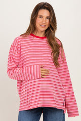 woman wearing a pink and red striped maternity top and holding her baby bump