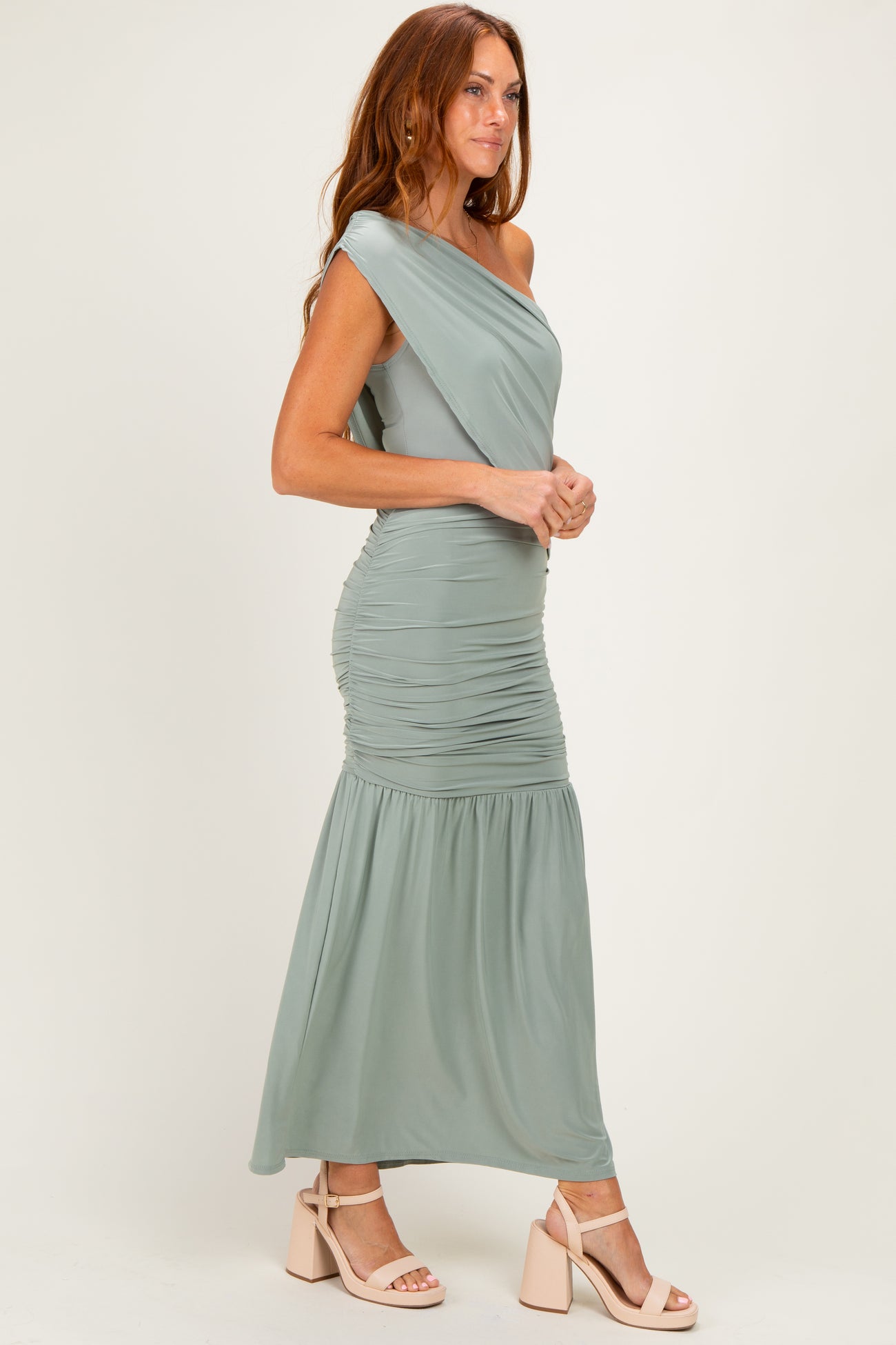 woman wearing a strapless sage green maxi dress with ruching details and a flowing skirt