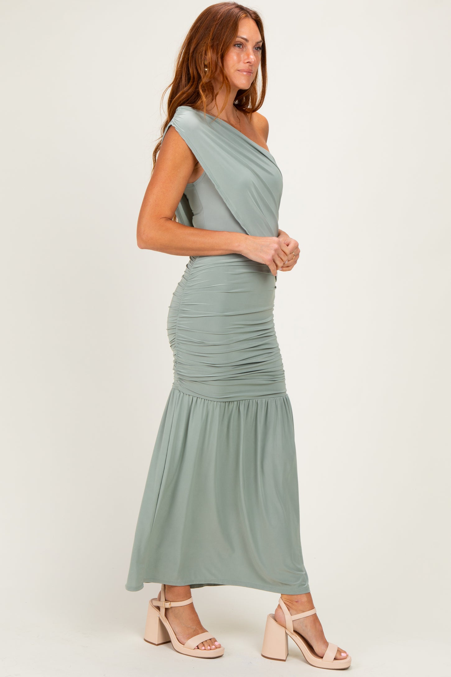 woman wearing a strapless sage green maxi dress with ruching details and a flowing skirt