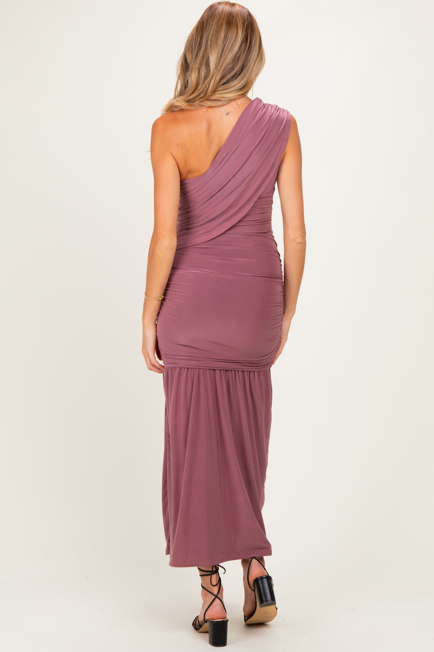 woman wearing a dusty rose one-shoulder maternity dress with a draped bodice and ruched skirt, showing a relaxed fit