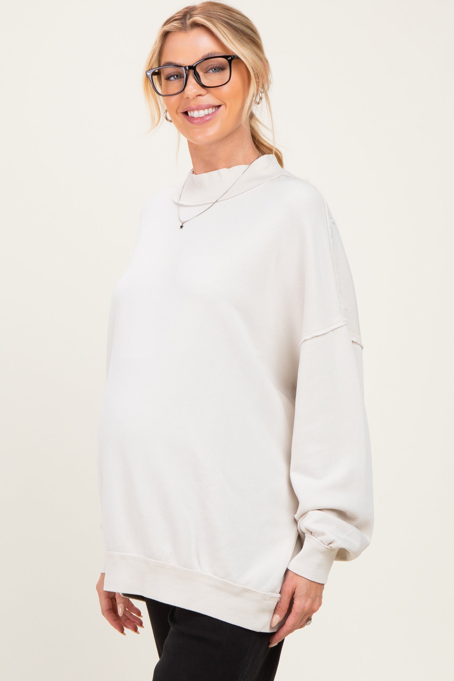 woman wearing a light grey maternity sweatshirt with a relaxed fit and a visible baby bump