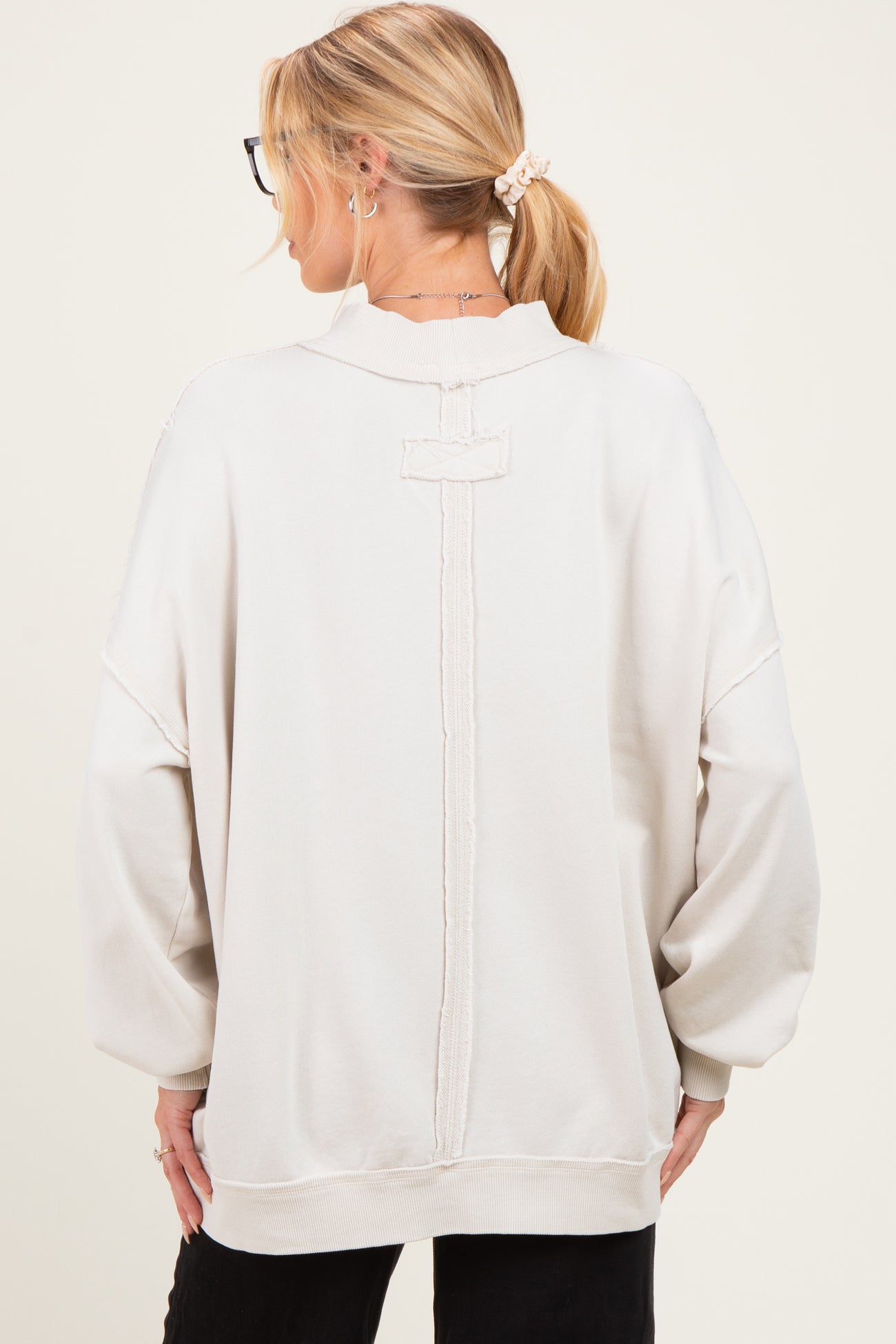 woman wearing a cream oversized maternity sweatshirt with a unique back design