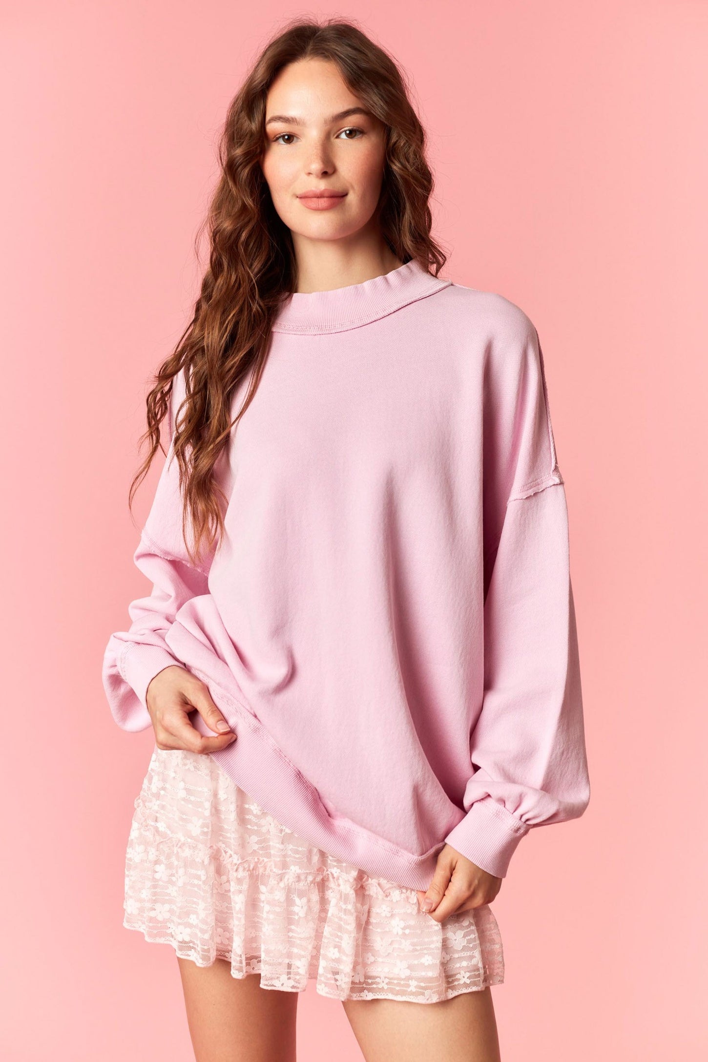 woman wearing a pastel pink oversized sweatshirt paired with a short, sparkly pink skirt