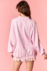 woman wearing a pink oversized sweatshirt with a back seam detail and long sleeves, styled over a lace trimmed skirt