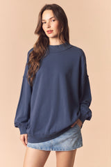 woman wearing a navy blue oversized sweatshirt with balloon sleeves and a relaxed fit paired with a denim mini skirt