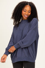 woman wearing a navy blue oversized sweatshirt with gathered sleeve details and a relaxed fit