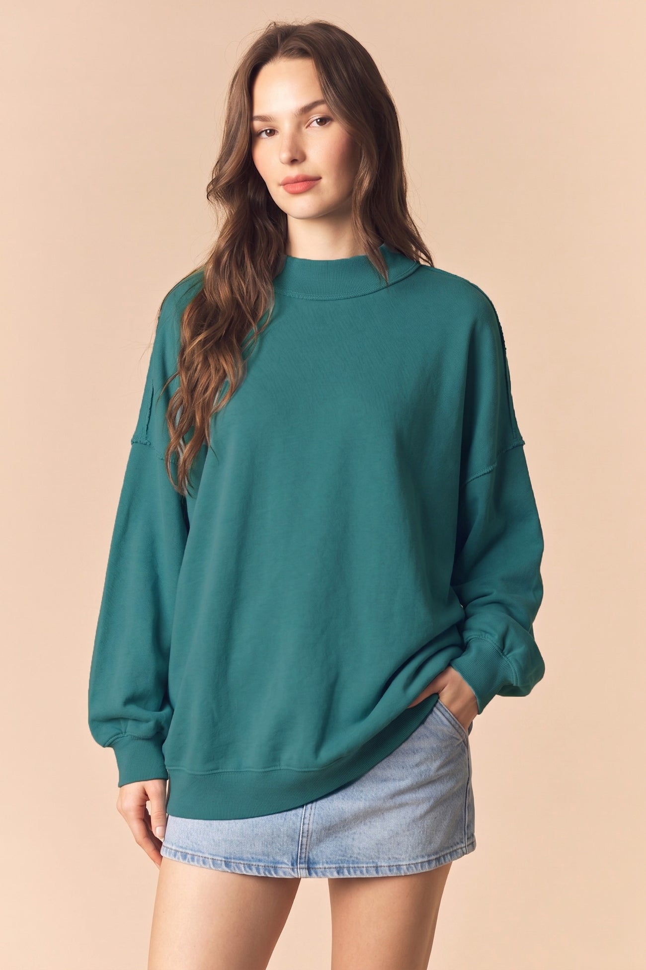 woman wearing a teal oversized sweatshirt and a light blue denim mini skirt