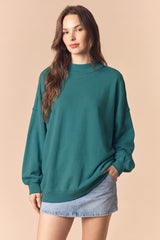 woman wearing a teal oversized sweatshirt and a light blue denim mini skirt