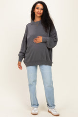 woman wearing a charcoal gray oversized maternity sweatshirt and blue jeans, holding her baby bump