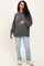 woman wearing a charcoal gray oversized maternity sweatshirt and blue jeans, holding her baby bump