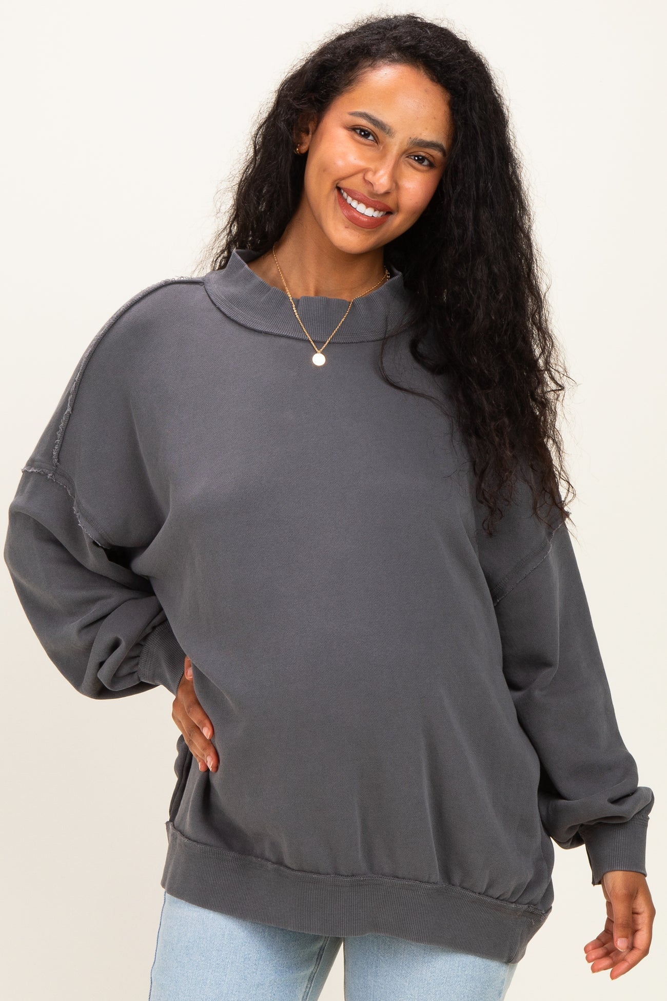 woman wearing a dark gray oversized maternity sweatshirt with a high neckline and relaxed fit, showing her baby bump