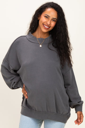 woman wearing a dark gray oversized maternity sweatshirt with a high neckline and relaxed fit, showing her baby bump