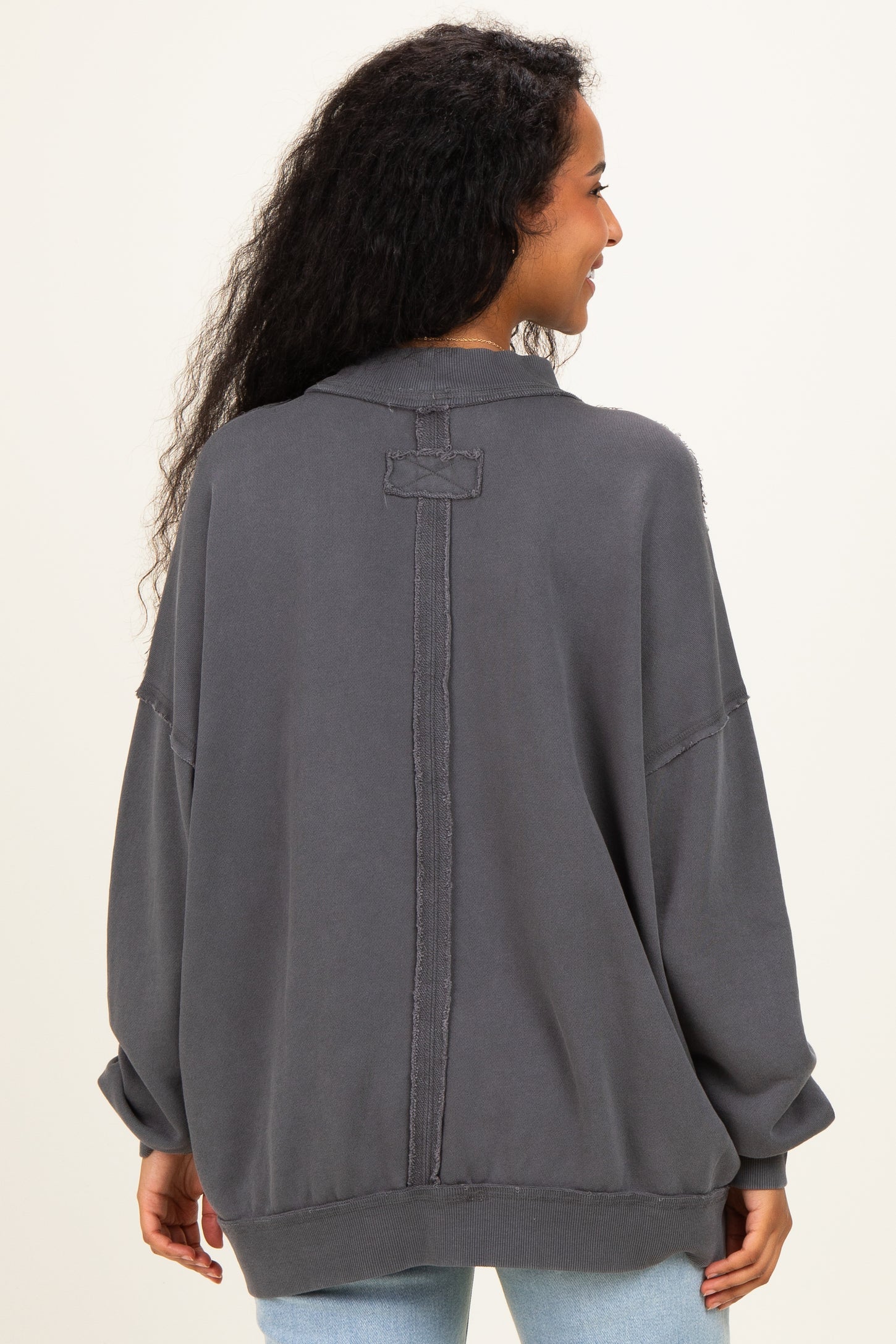 woman wearing a dark gray oversized maternity sweatshirt with a relaxed fit and back seam detail