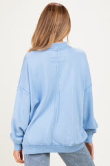 woman wearing a light blue oversized maternity sweatshirt with a relaxed fit and back seam detailing