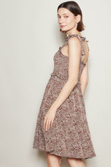 woman wearing a brown floral spaghetti strap dress with ruffled details and a fitted bodice