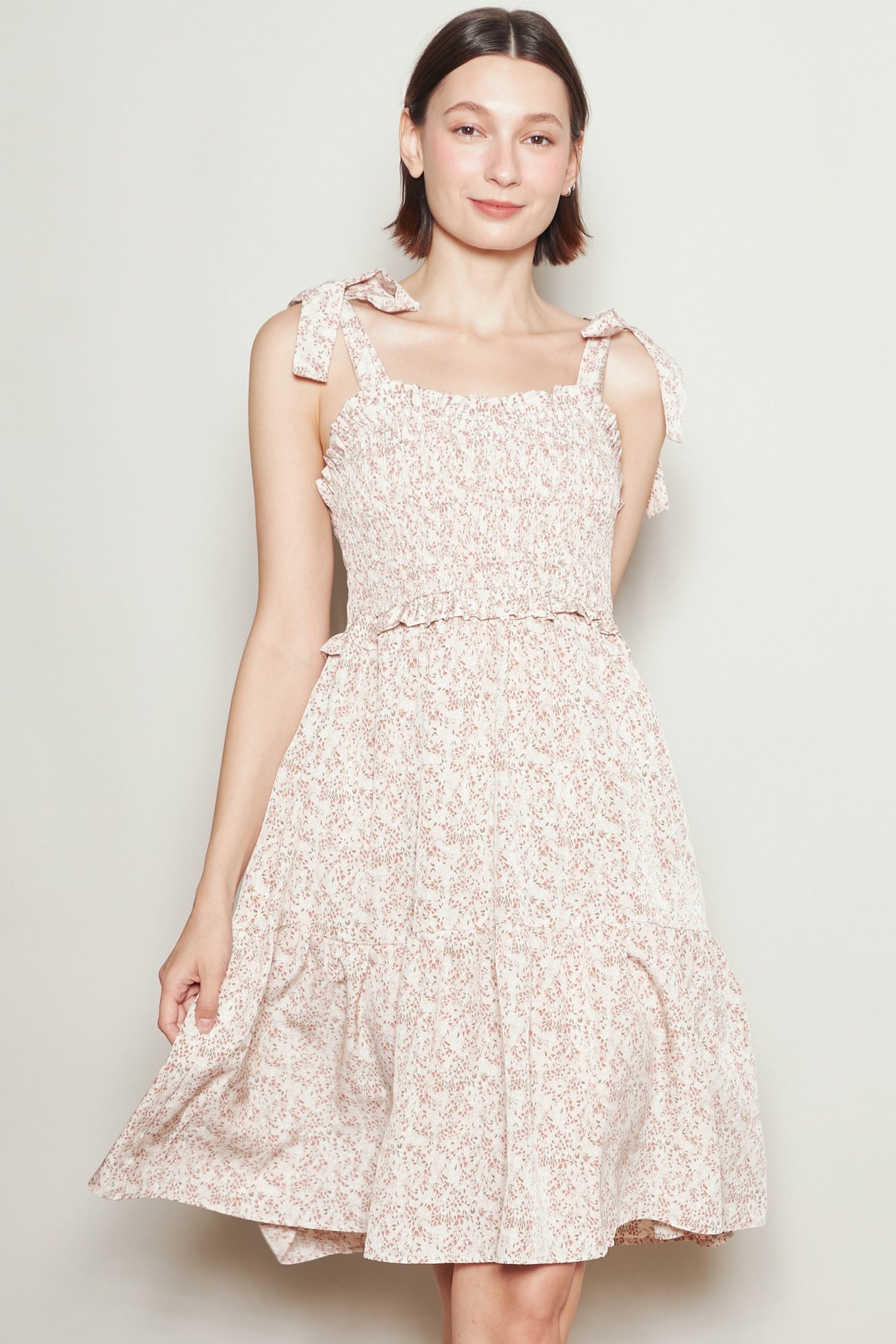woman wearing a pink floral sundress with ruffled details and tie straps