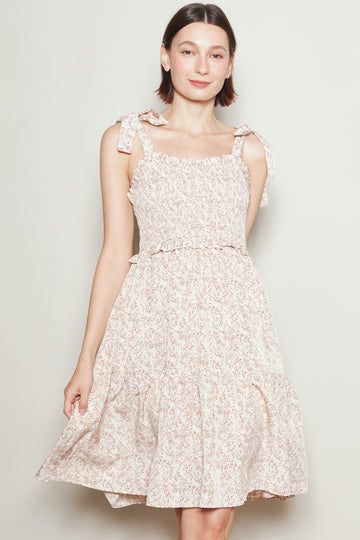 woman wearing a pink floral sundress with ruffled details and tie straps