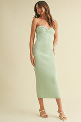 woman wearing a light green strapless ribbed midi dress with a twist front detail and strappy heels