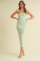woman wearing a mint green strapless ribbed midi dress with a front twist detail and strappy sandals