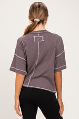woman wearing a loose-fitting dark gray maternity top with short sleeves and contrasting stitching details