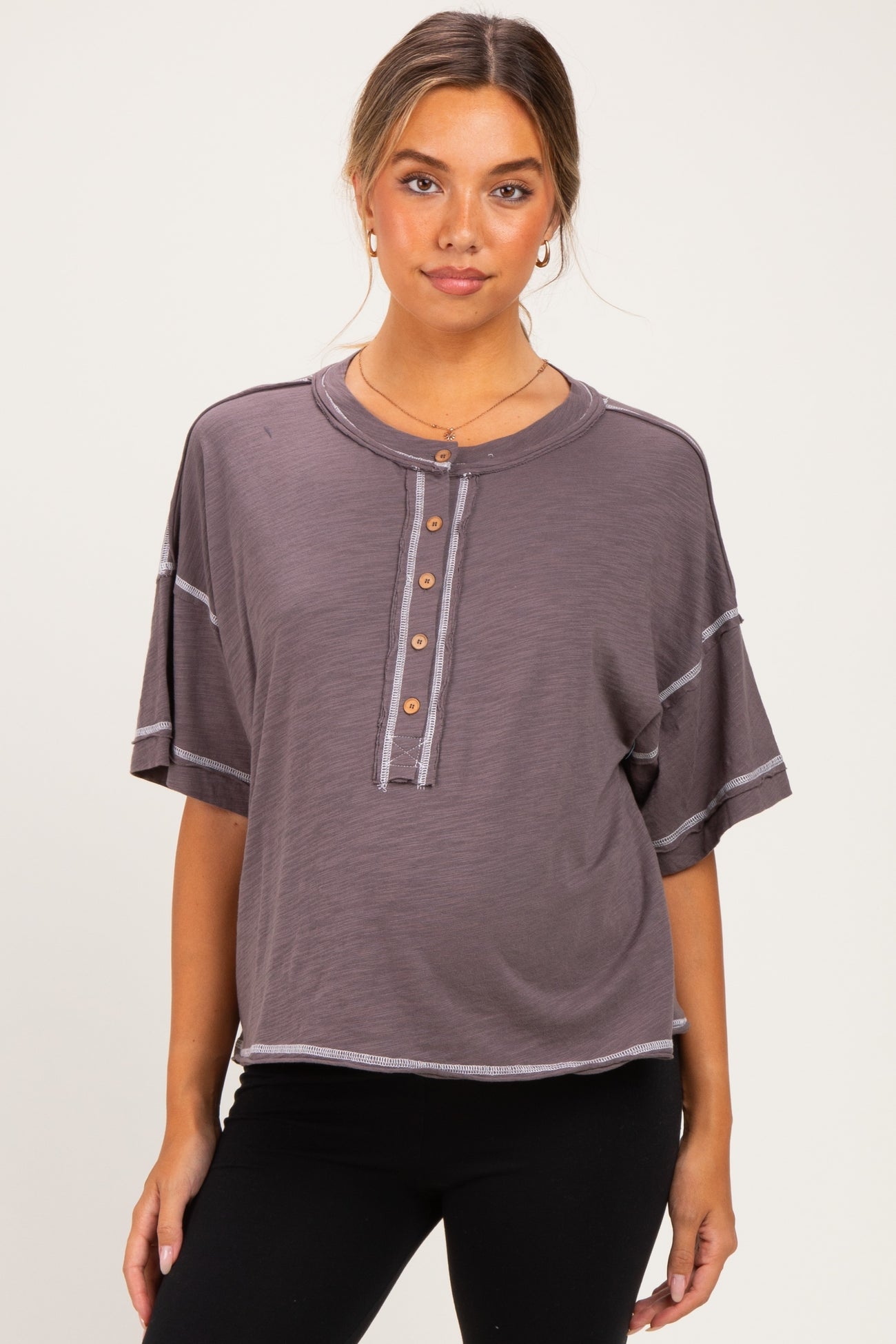 woman wearing a gray maternity wear short sleeve henley top with button details and contrasting stitching