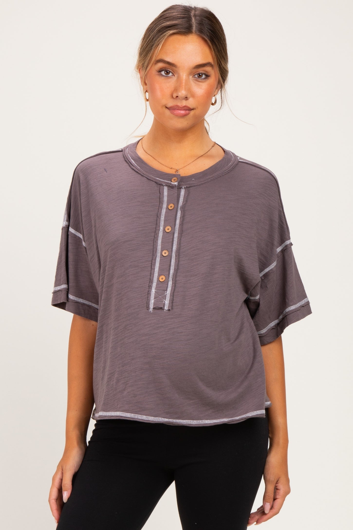 woman wearing a gray maternity wear short sleeve henley top with button details and contrasting stitching