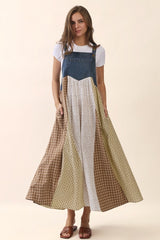 woman wearing a color-blocked maxi dress with a denim top and patterned skirt, standing with pockets