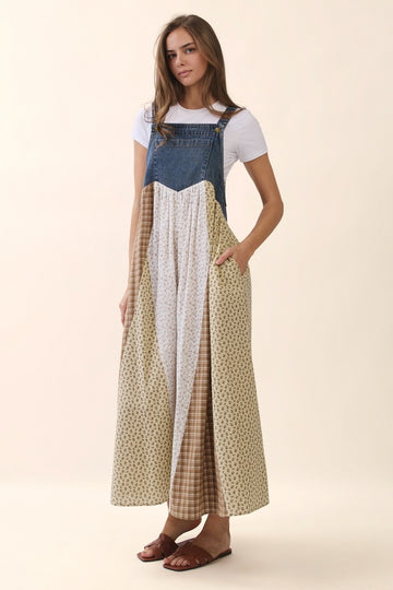 woman wearing a denim maxi dress with a patterned skirt and white t-shirt underneath, standing against a light backdrop