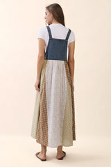 woman wearing a denim sleeveless dress with a patterned, multicolor skirt and a white t-shirt underneath