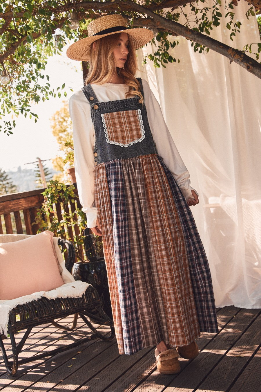 woman wearing a denim plaid maxi dress with a lace pocket and a wide-brimmed straw hat