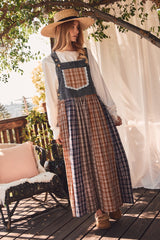 woman wearing a denim plaid maxi dress with a lace pocket and a wide-brimmed straw hat